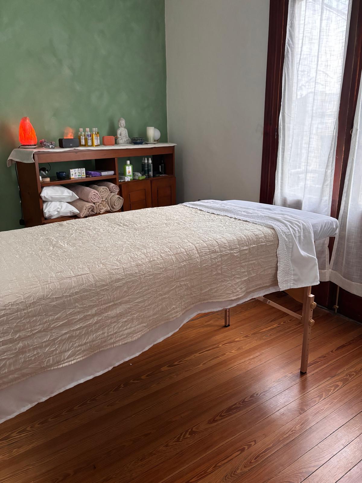 La sala de masajes de Serena: camilla con manta crema, toallas, aceites y una lámpara de sal